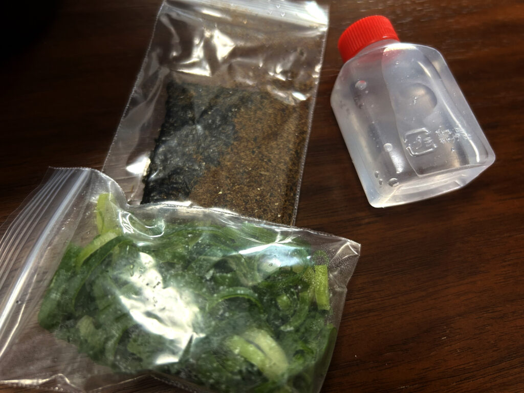 別添えの刻みネギ、魚粉、海苔、麺のほぐし水が入った小ボトル