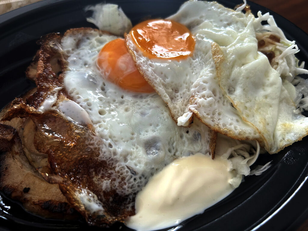 香ばしく焼かれたチャーシューの上にのった2つの半熟目玉焼き