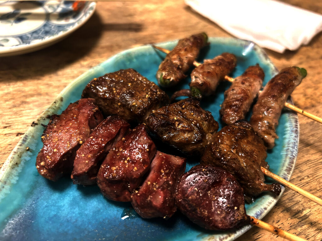 青い皿に盛られた末廣ブルースの絶妙な焼き加減のレバー・ハツ・野菜巻き串
