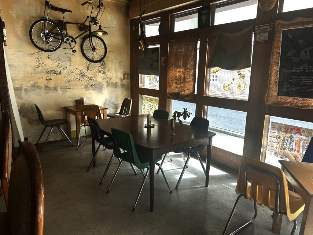 喫茶+バー よんぱちPANの広々としたテーブル席と壁に掛けられた自転車