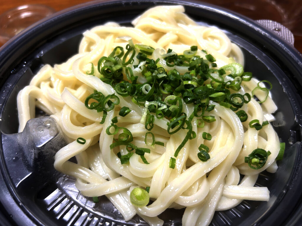 名代 かすうどん なが田の温玉かすうどんの中蓋に乗った麺と青ネギ